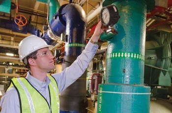 Man in white hard hat inspecting equipment.
